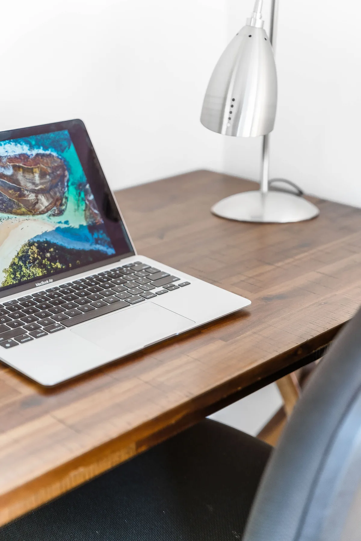 A laptop and desk lamp sit on a wooden desk.