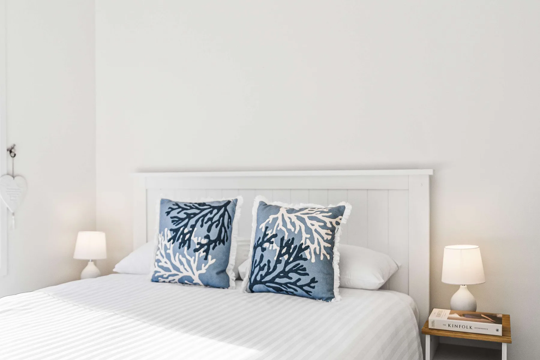A bedroom with a neatly made bed and blue patterned pillows.