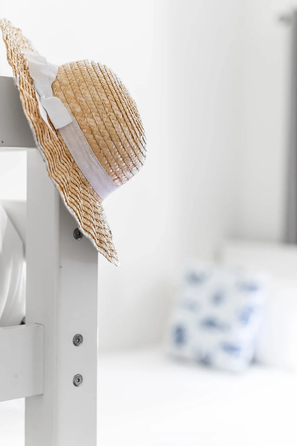 A bright indoor seating area with a woven hat hanging from a white chair.