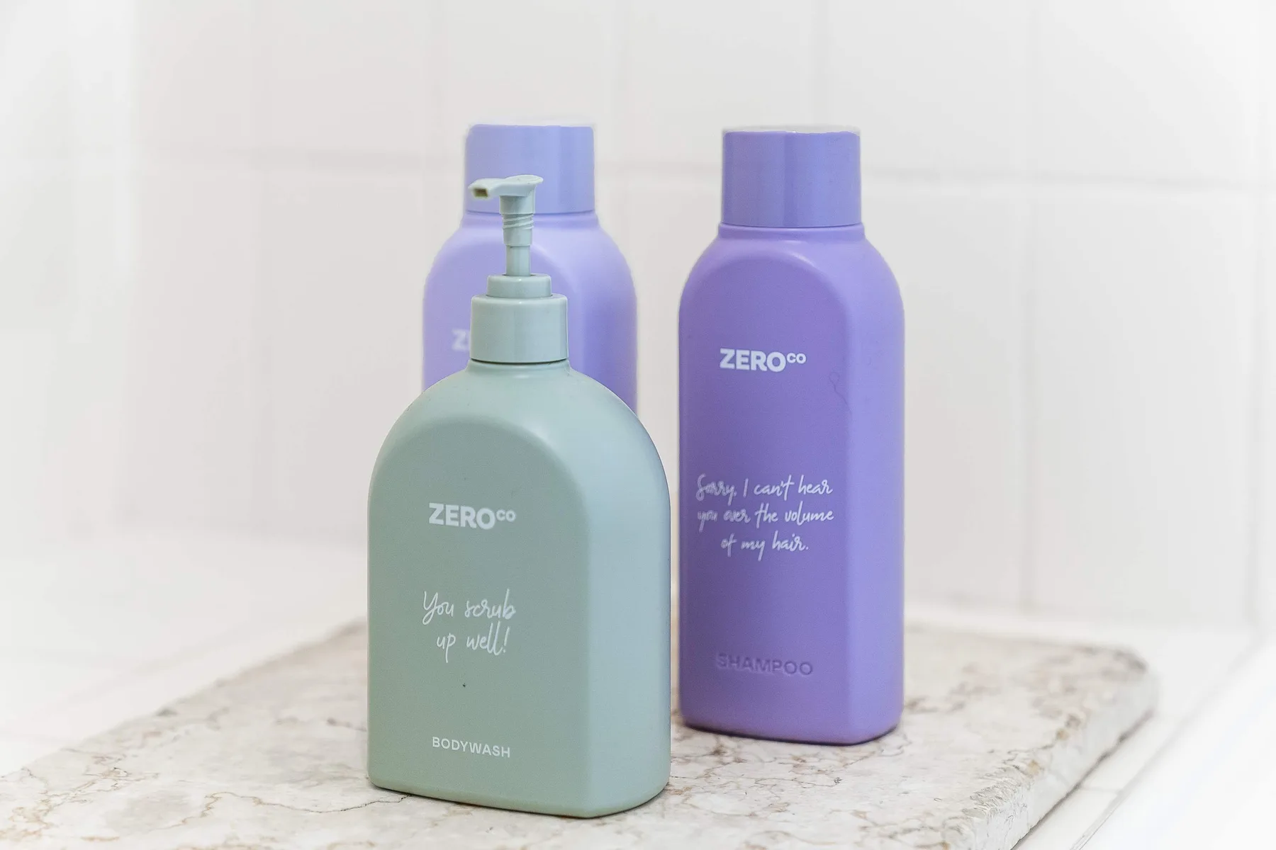 Bottles of bath products are arranged on a marble bathroom counter.