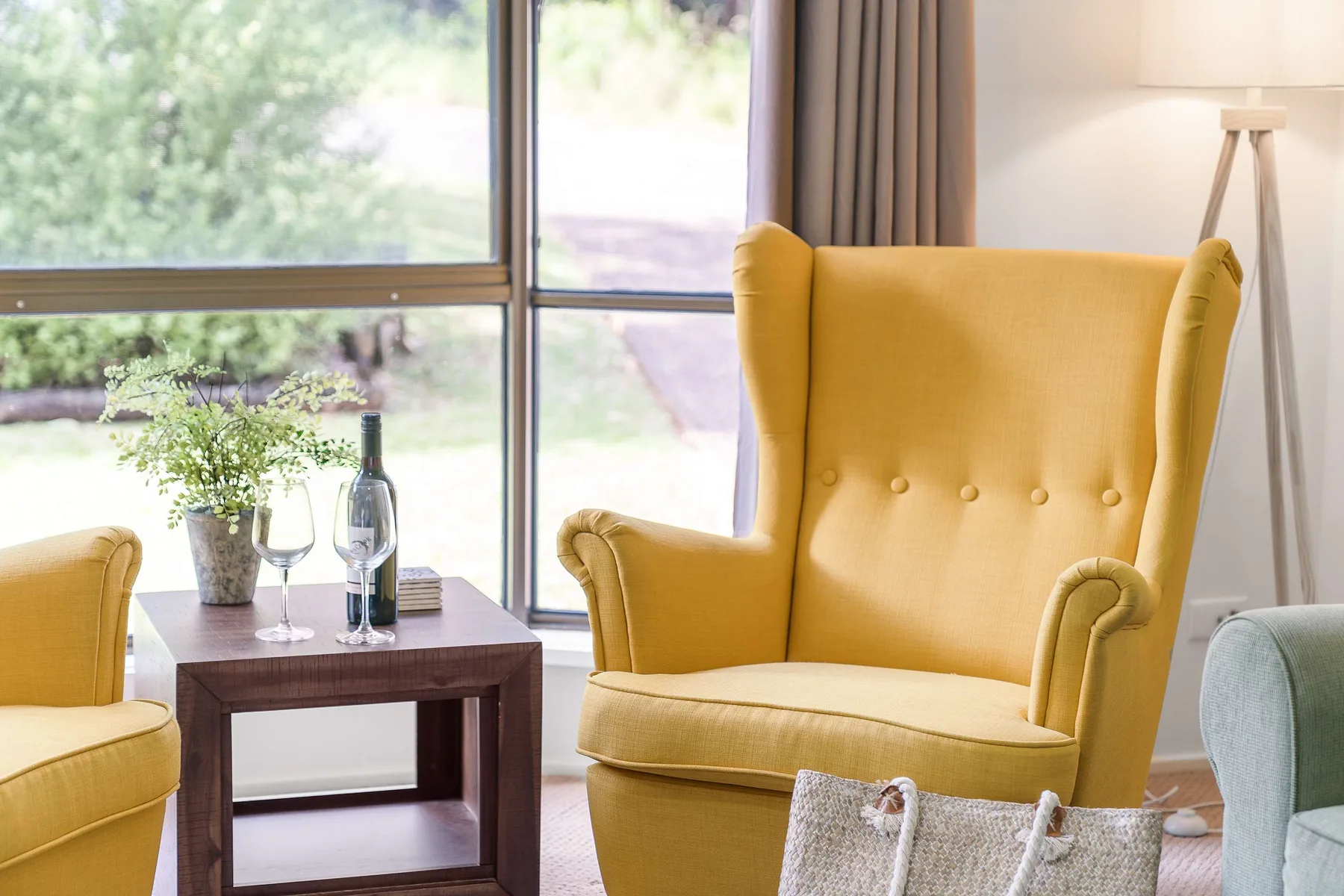 A bright living room with yellow seating beside a large window.