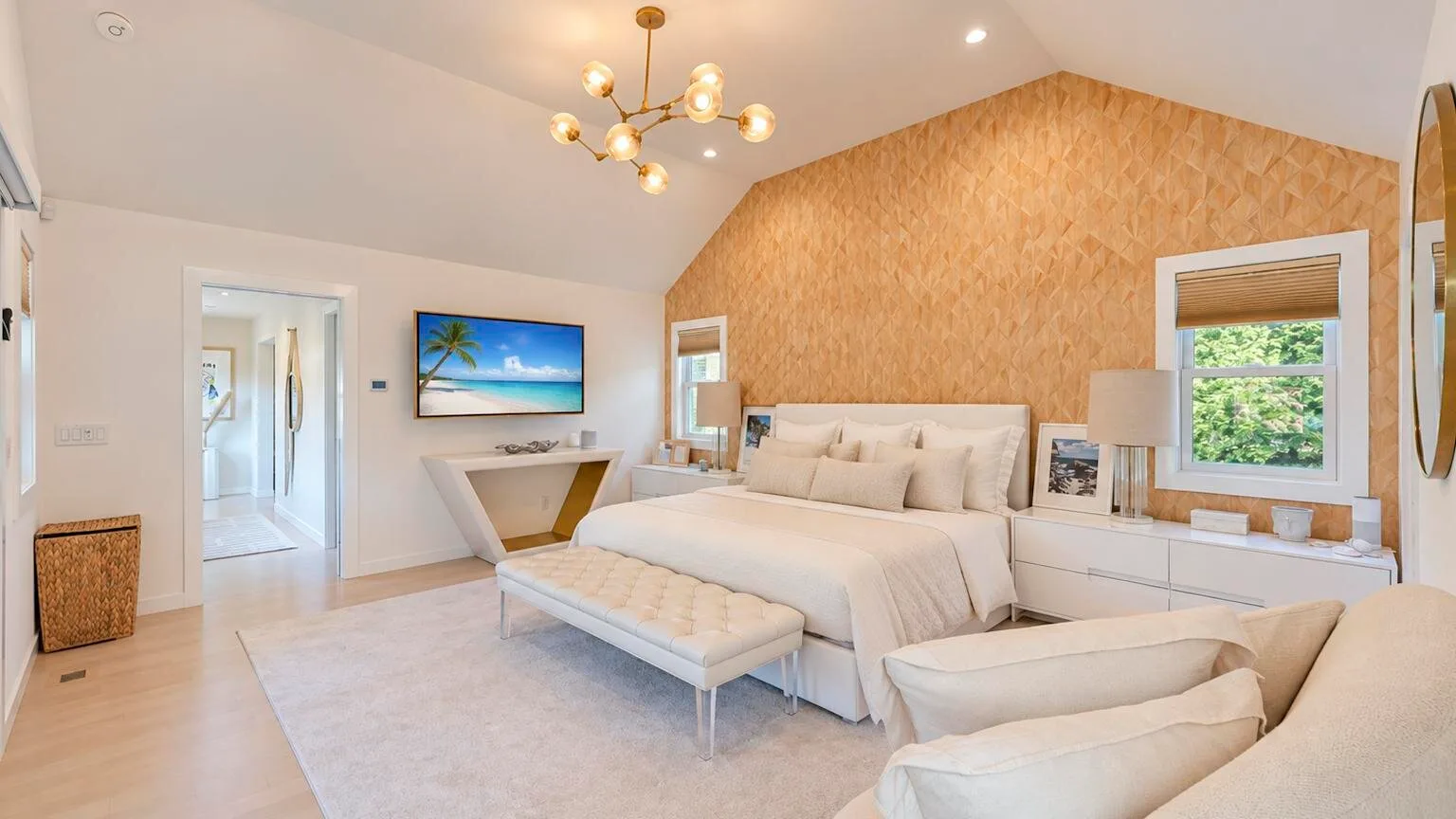 Un dormitorio luminoso con una cama grande, muebles claros y una pared decorativa texturizada.