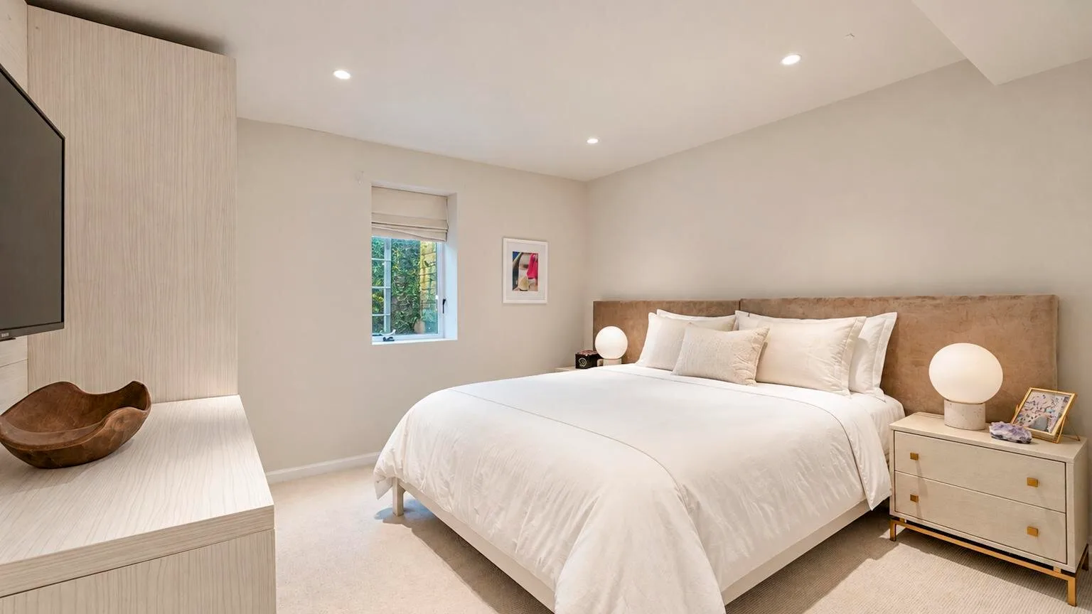 Un dormitorio luminoso con una cama bien tendida y una ventana al lado.