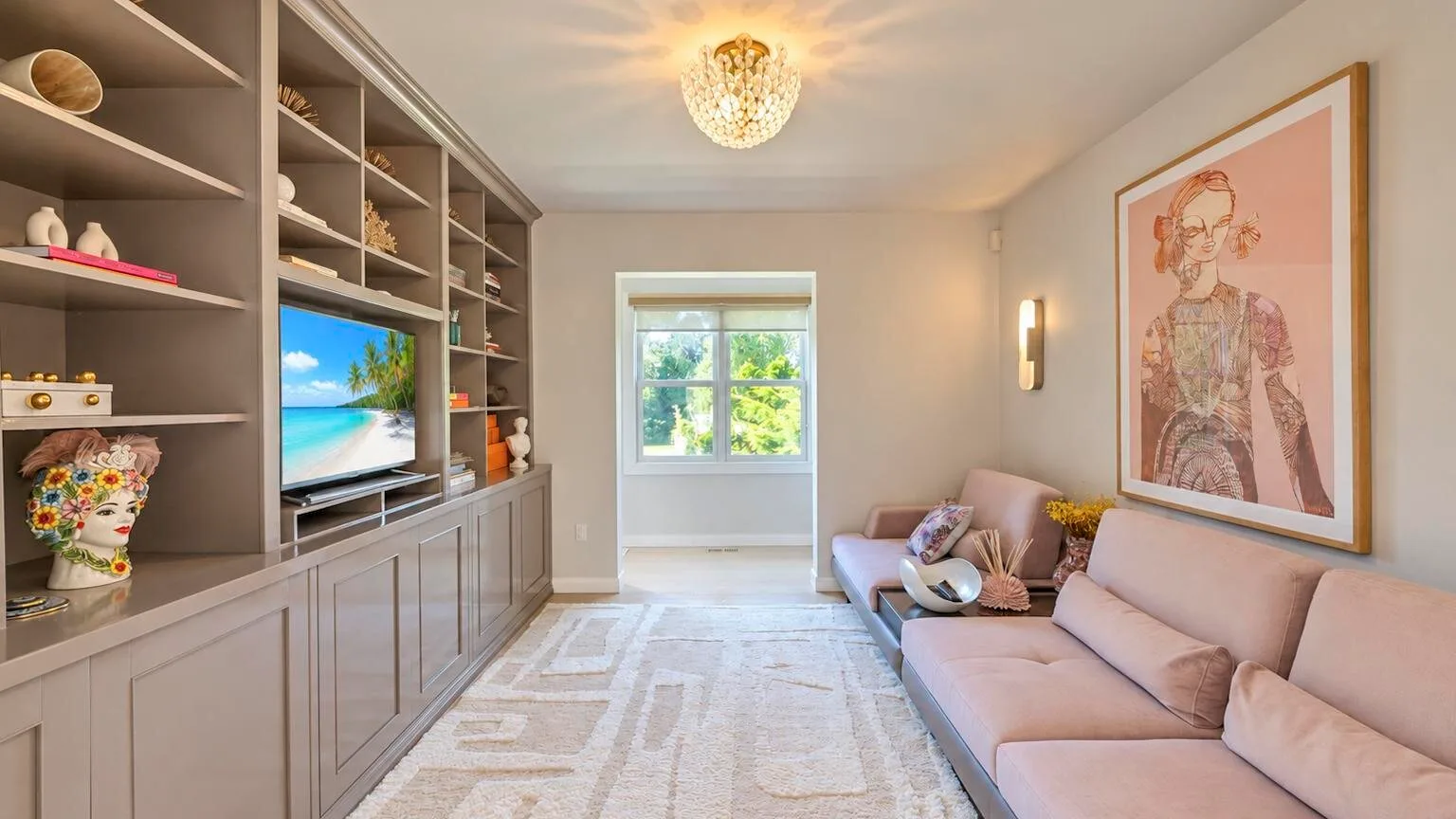 Una sala de estar con estanterías empotradas, un televisor y asientos junto a la ventana.