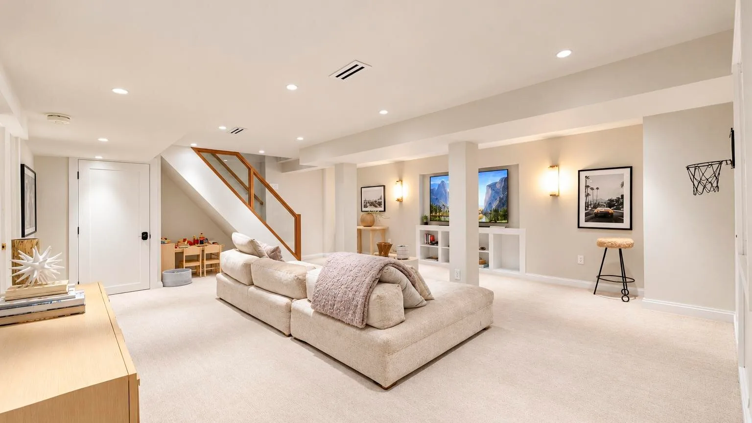 Una sala luminosa con asientos neutros y una escalera junto a la pared del fondo.