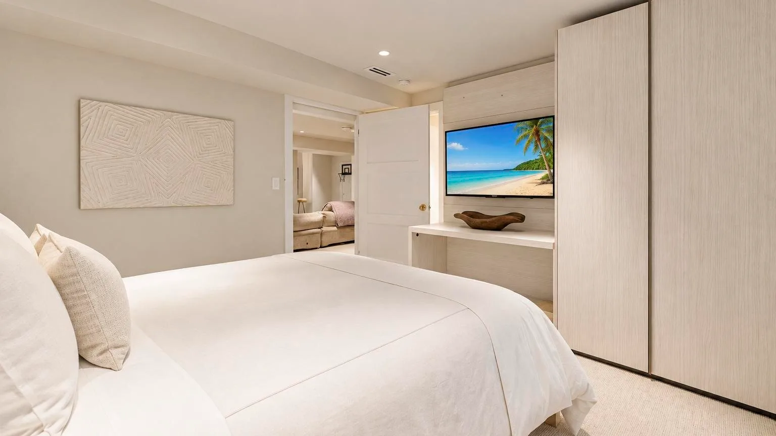 Un dormitorio luminoso tiene una cama bien tendida y una colorida escena de playa en el televisor.