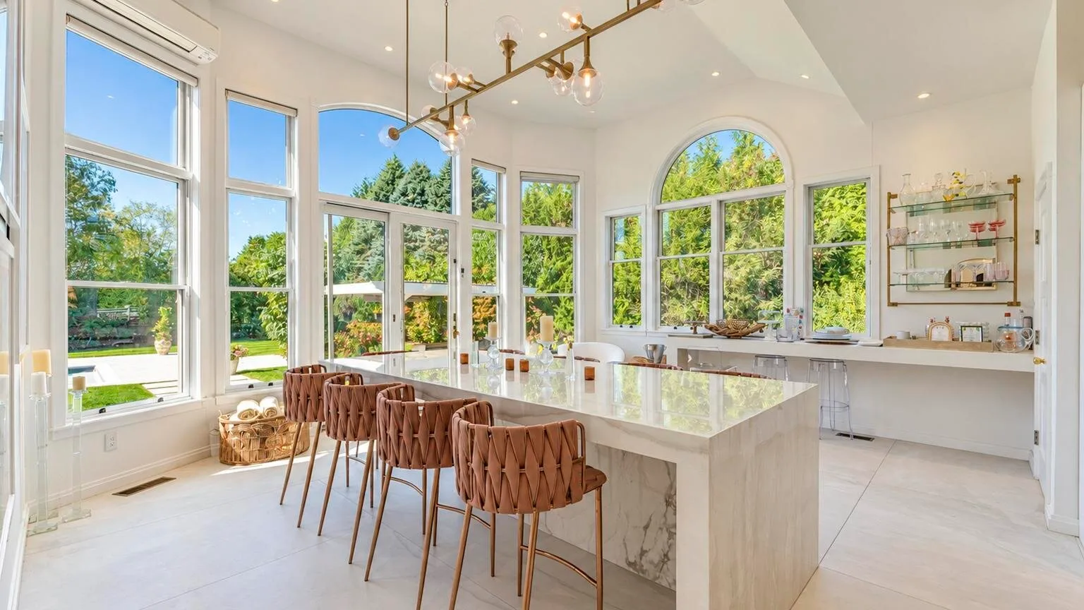 Una cocina luminosa con una gran isla y asientos junto a ventanas altas.
