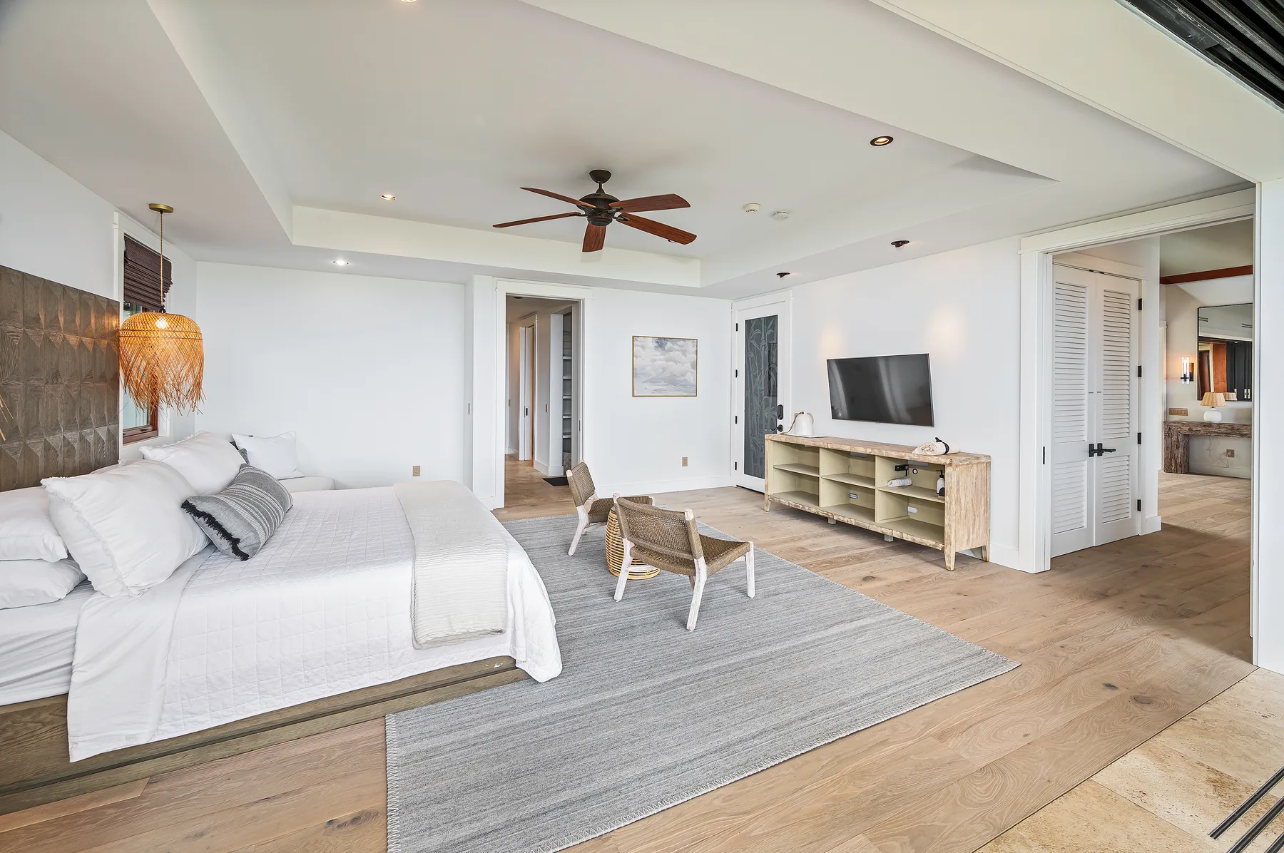 A bright bedroom with a bed, seating area, and television on a low console.