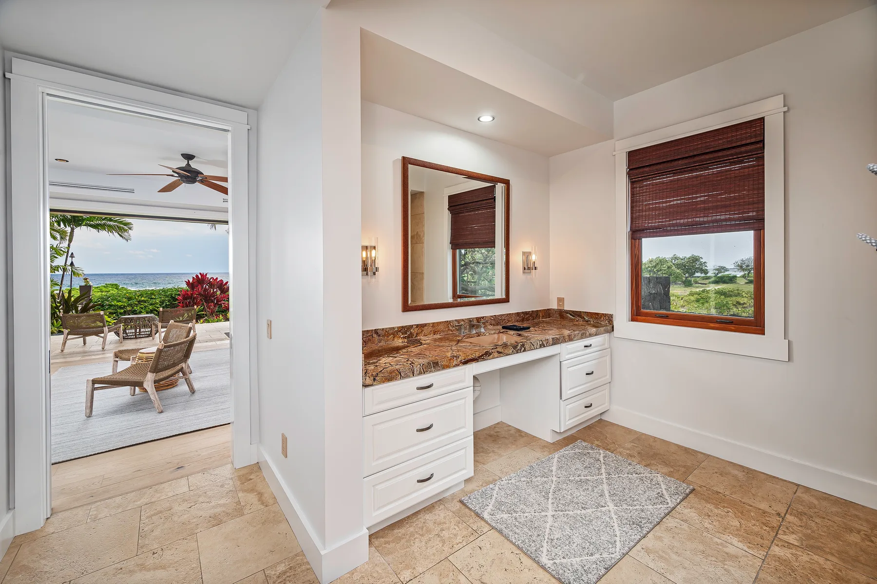 A bright bathroom vanity area with a mirror, countertop, and window.