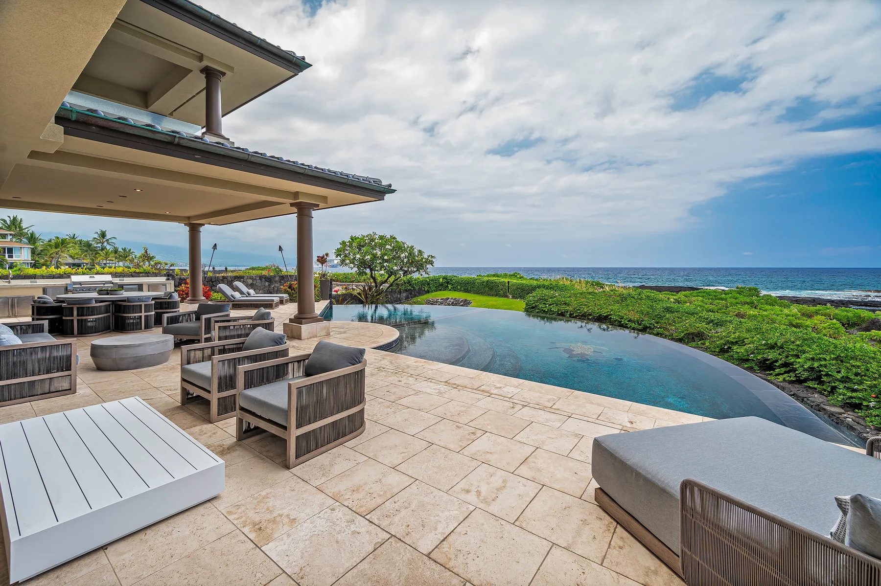 An outdoor terrace beside an infinity pool overlooks the ocean.