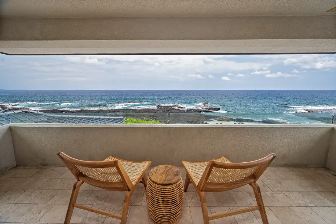 A balcony seating area overlooks the ocean.