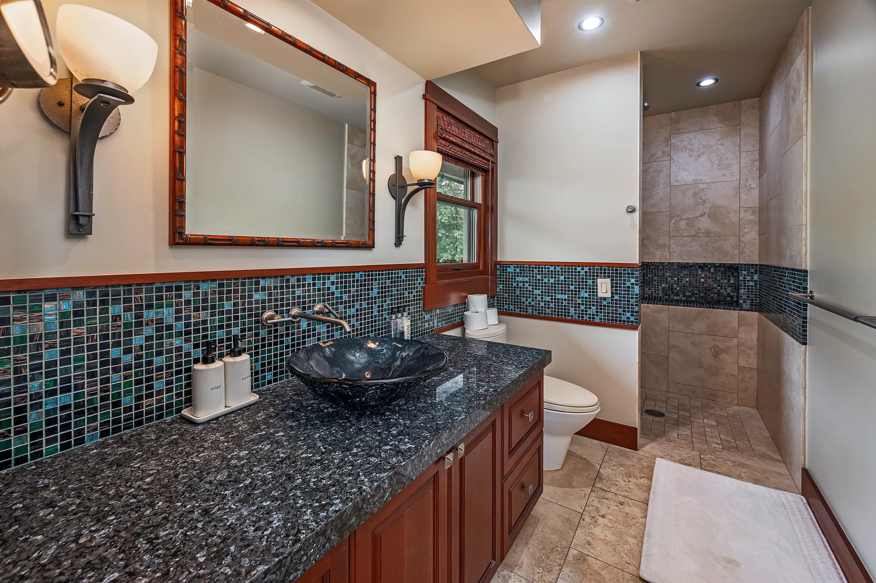A bathroom with a long vanity, a sink, and a tiled shower.