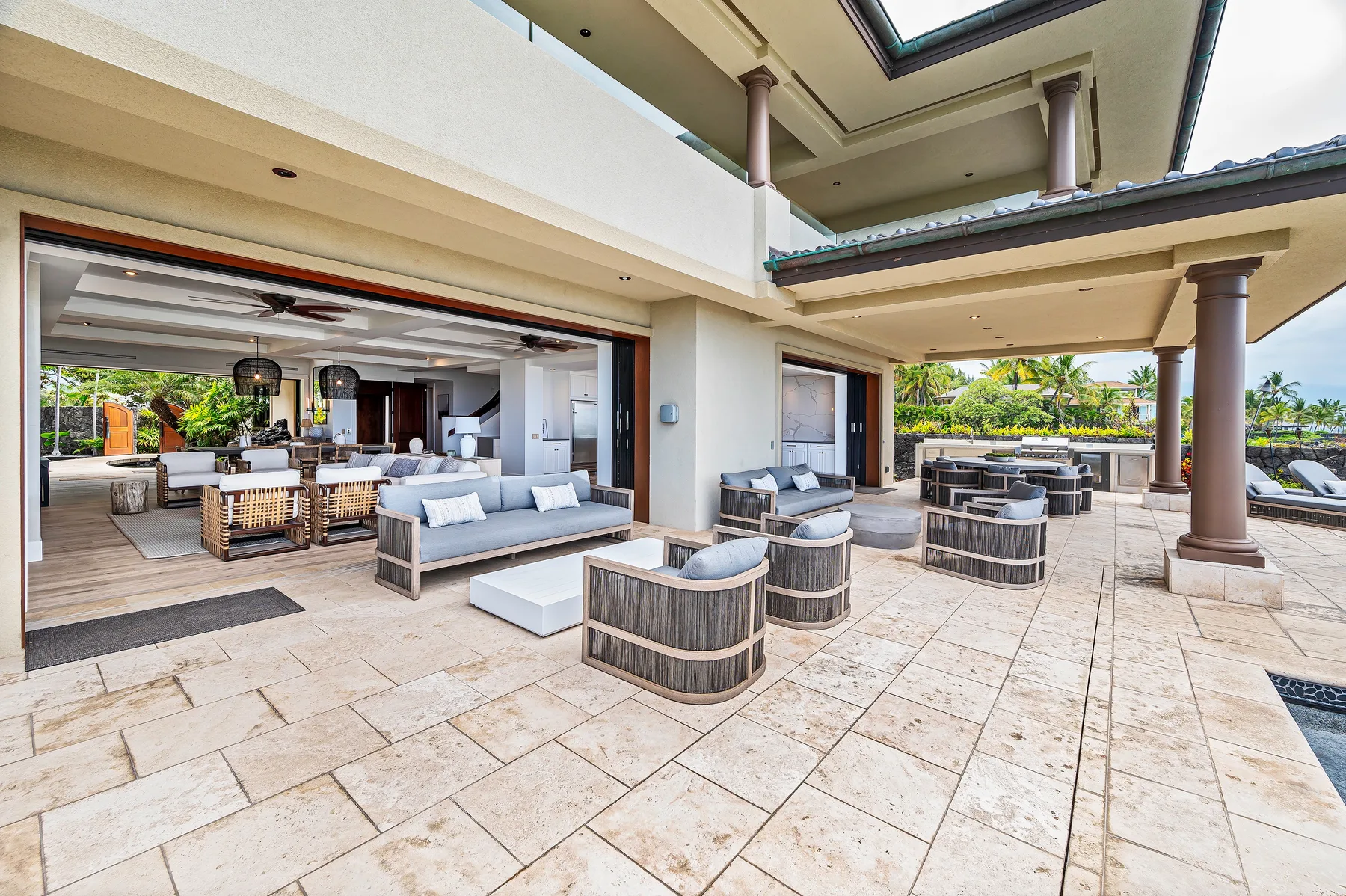 An open-air patio with lounge seating and a dining area beside the house.