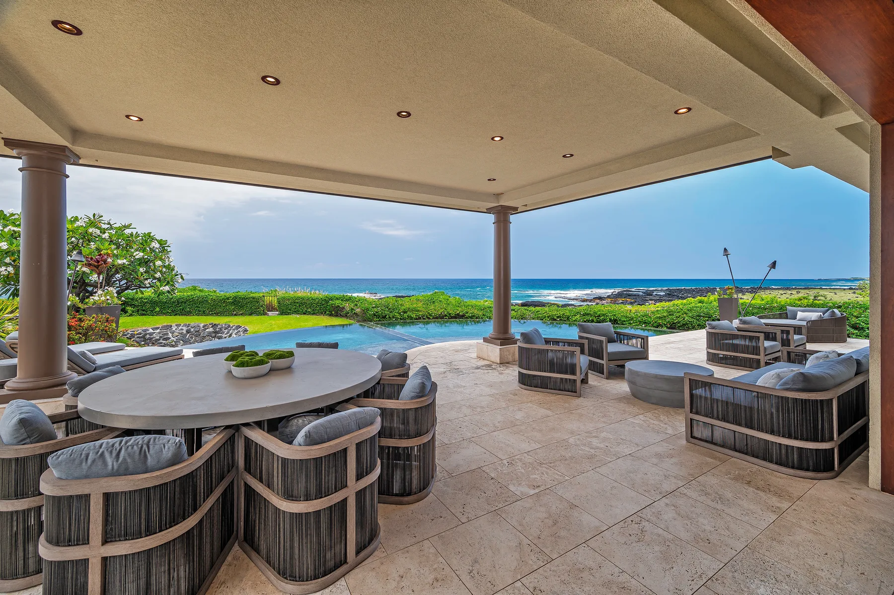 A covered outdoor patio overlooks the ocean, with tables and seating.