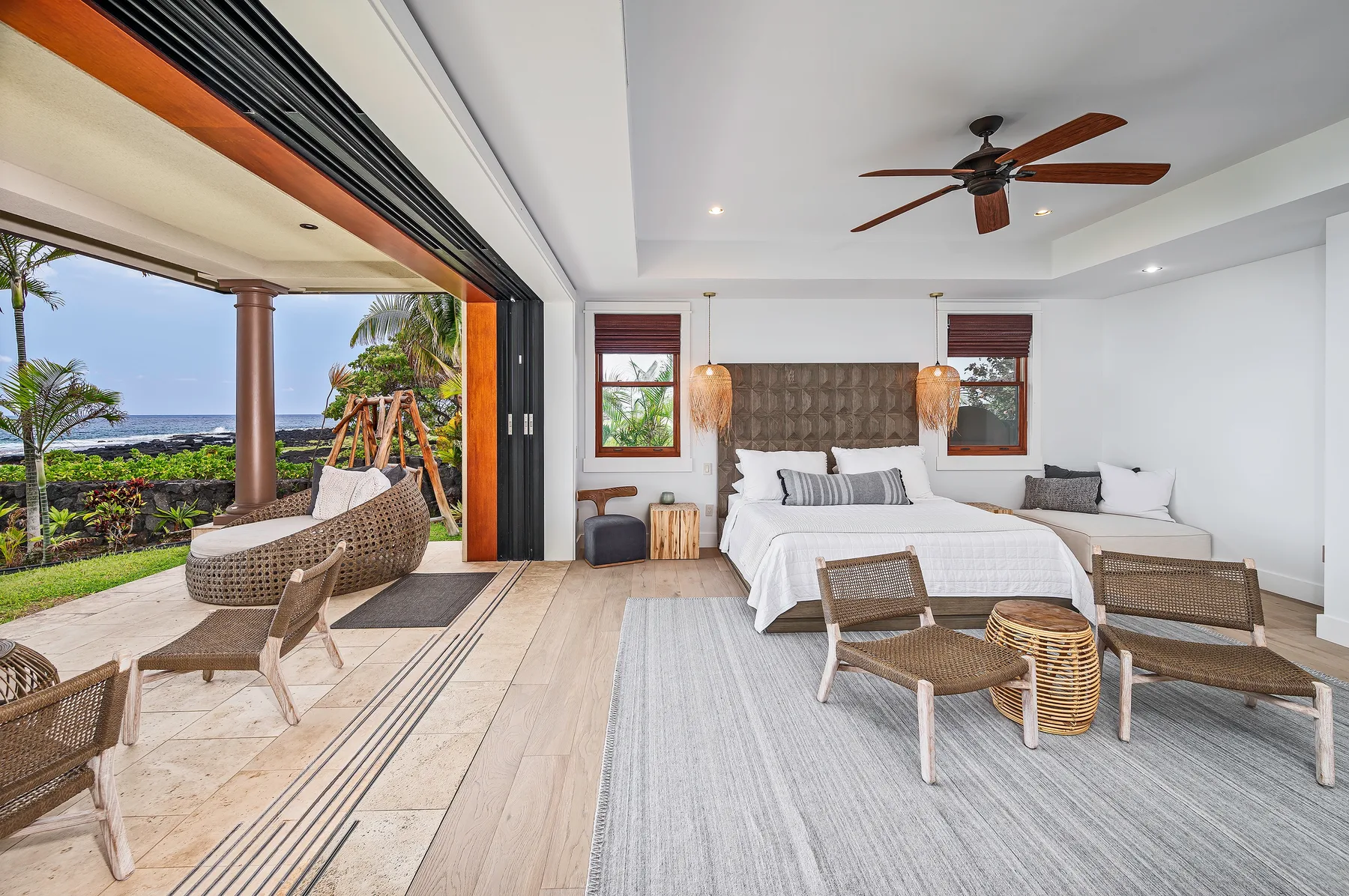 A bright bedroom opens onto a patio, with a bed and outdoor seating.