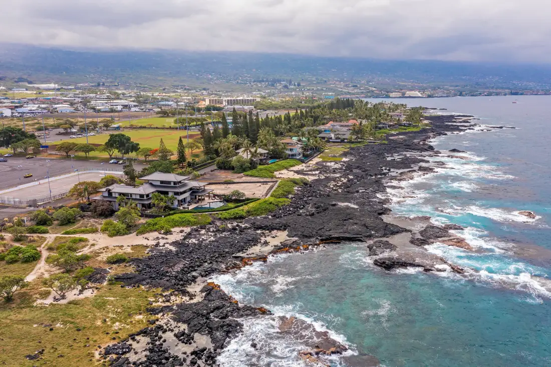 A rocky coastline with waves, buildings, and a town stretching inland.