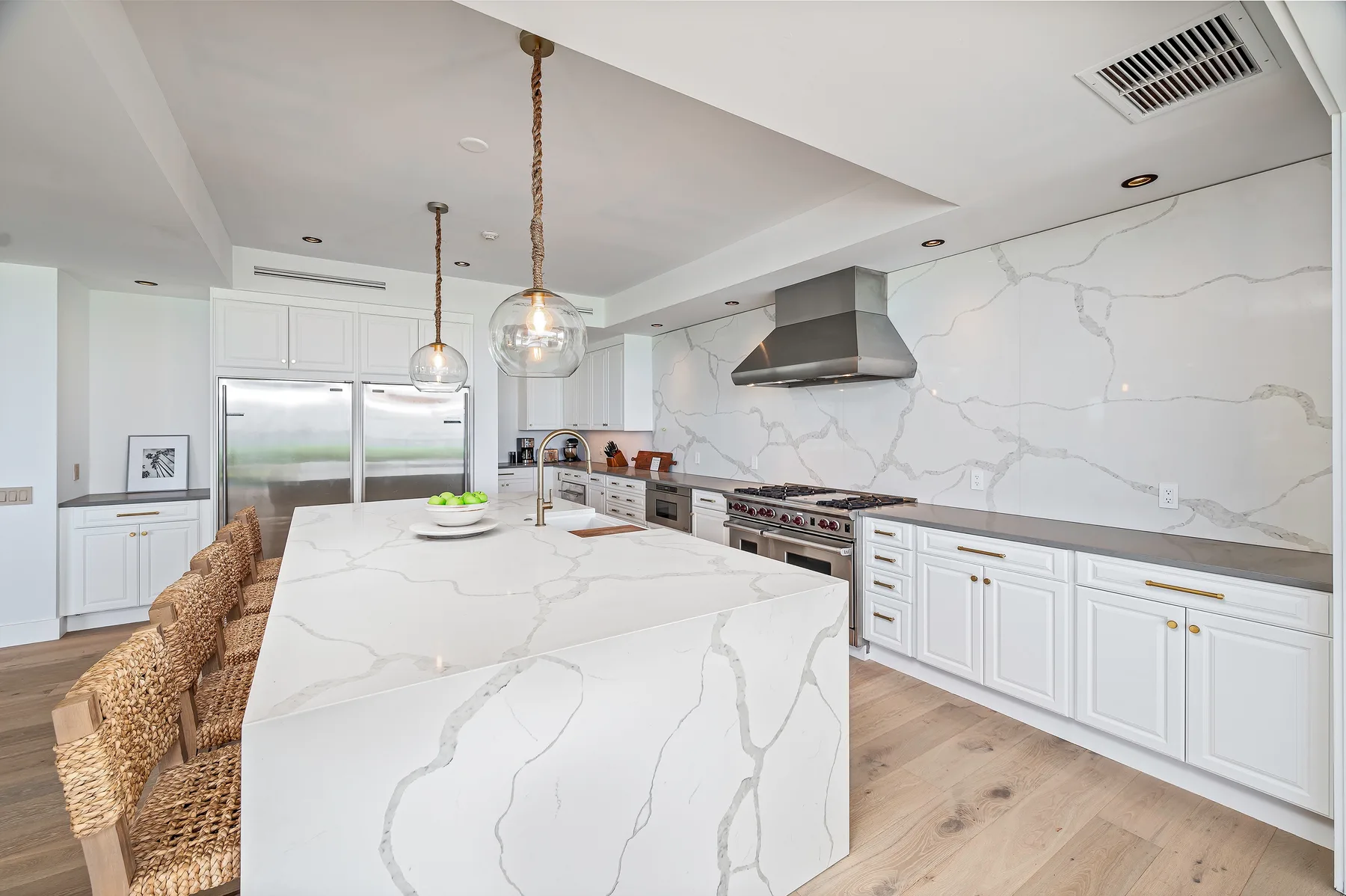 A bright kitchen with a large island, white cabinetry, and stainless steel appliances.
