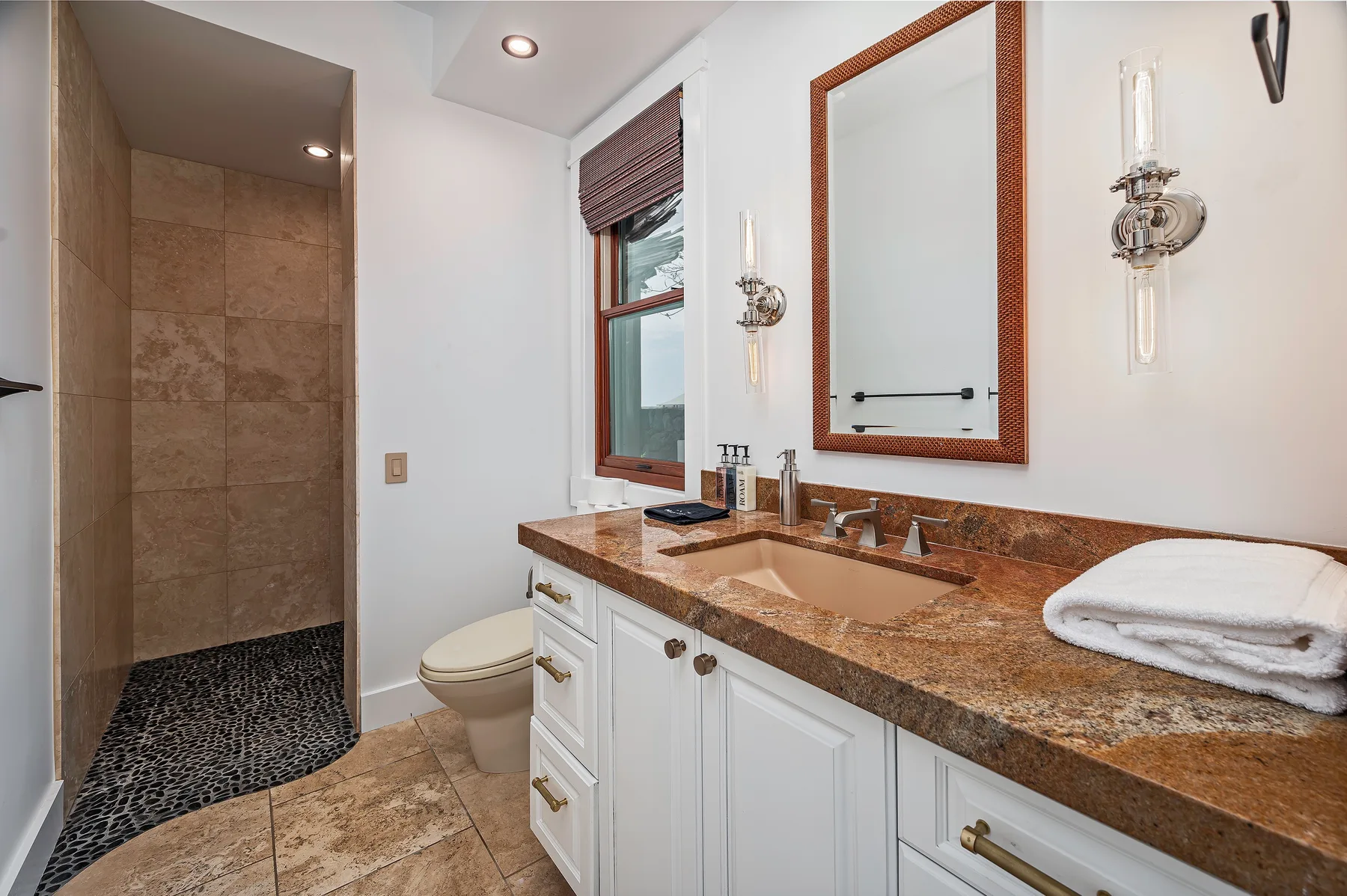 A bathroom with a long vanity, mirror, and walk-in shower.