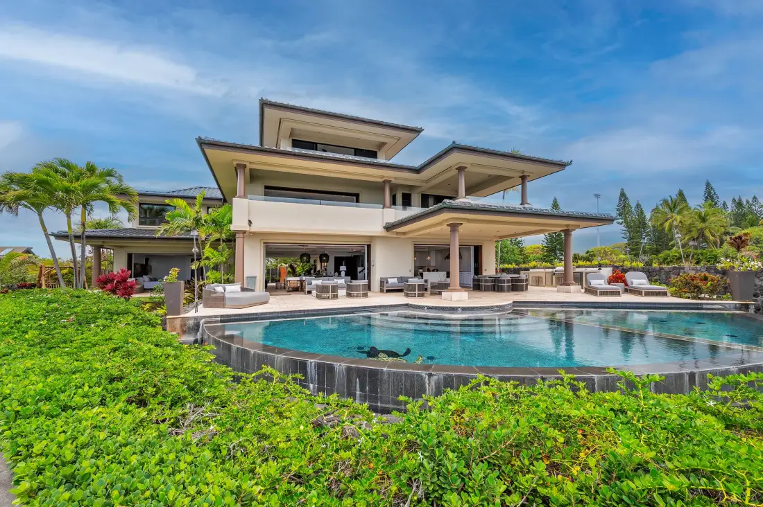 A modern house with a swimming pool, patio seating, and landscaped gardens.