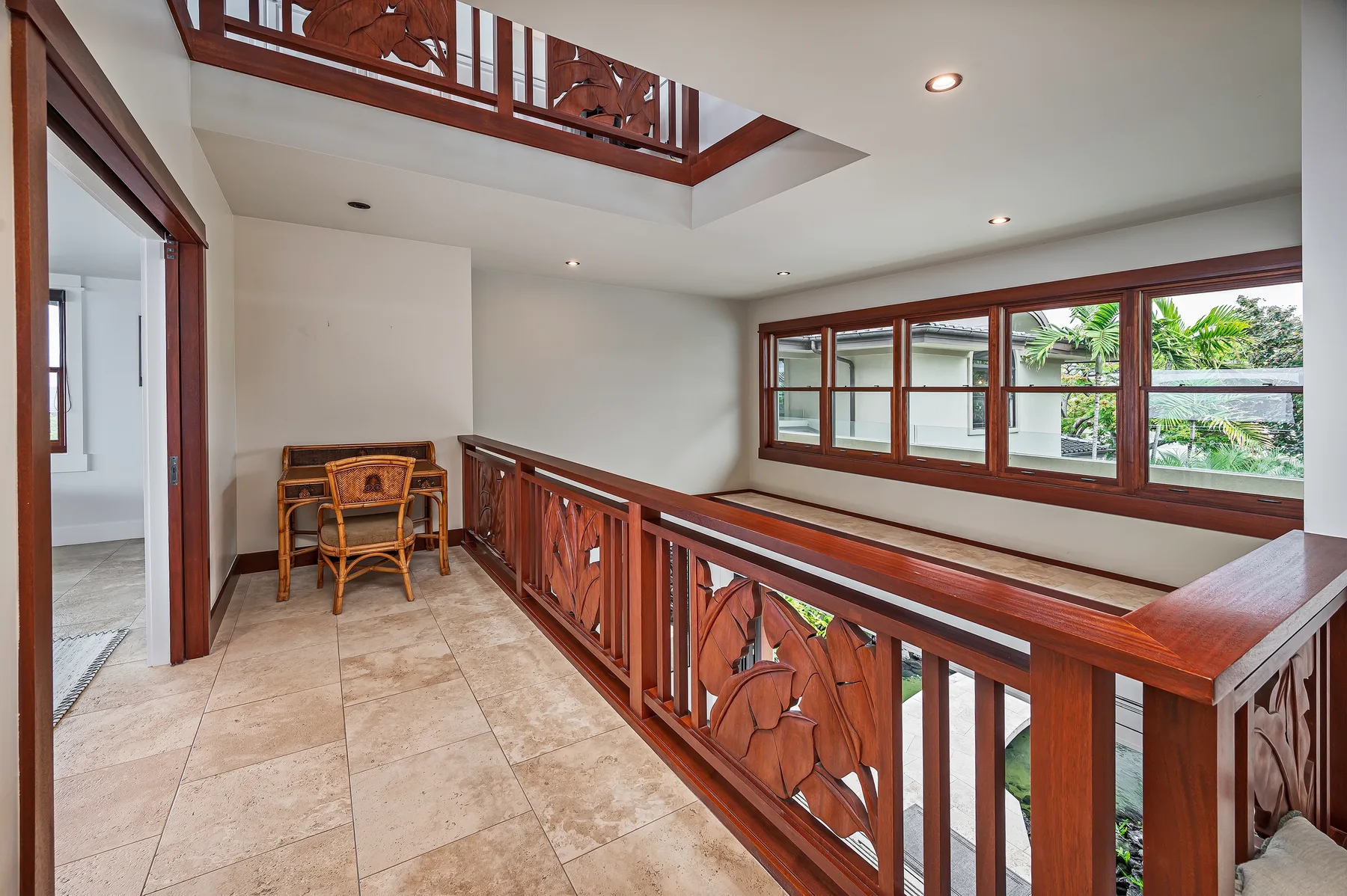 An interior balcony with carved wooden railings and large windows.
