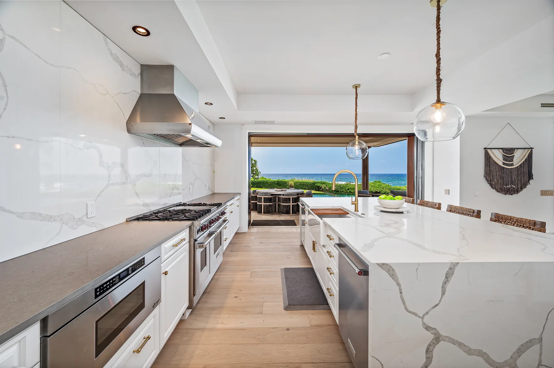 A bright kitchen with a large island and a wide window overlooking the water.