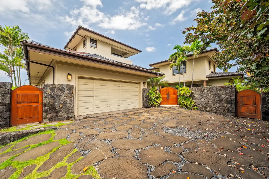A house exterior with a wide garage door and a stone-paved driveway.