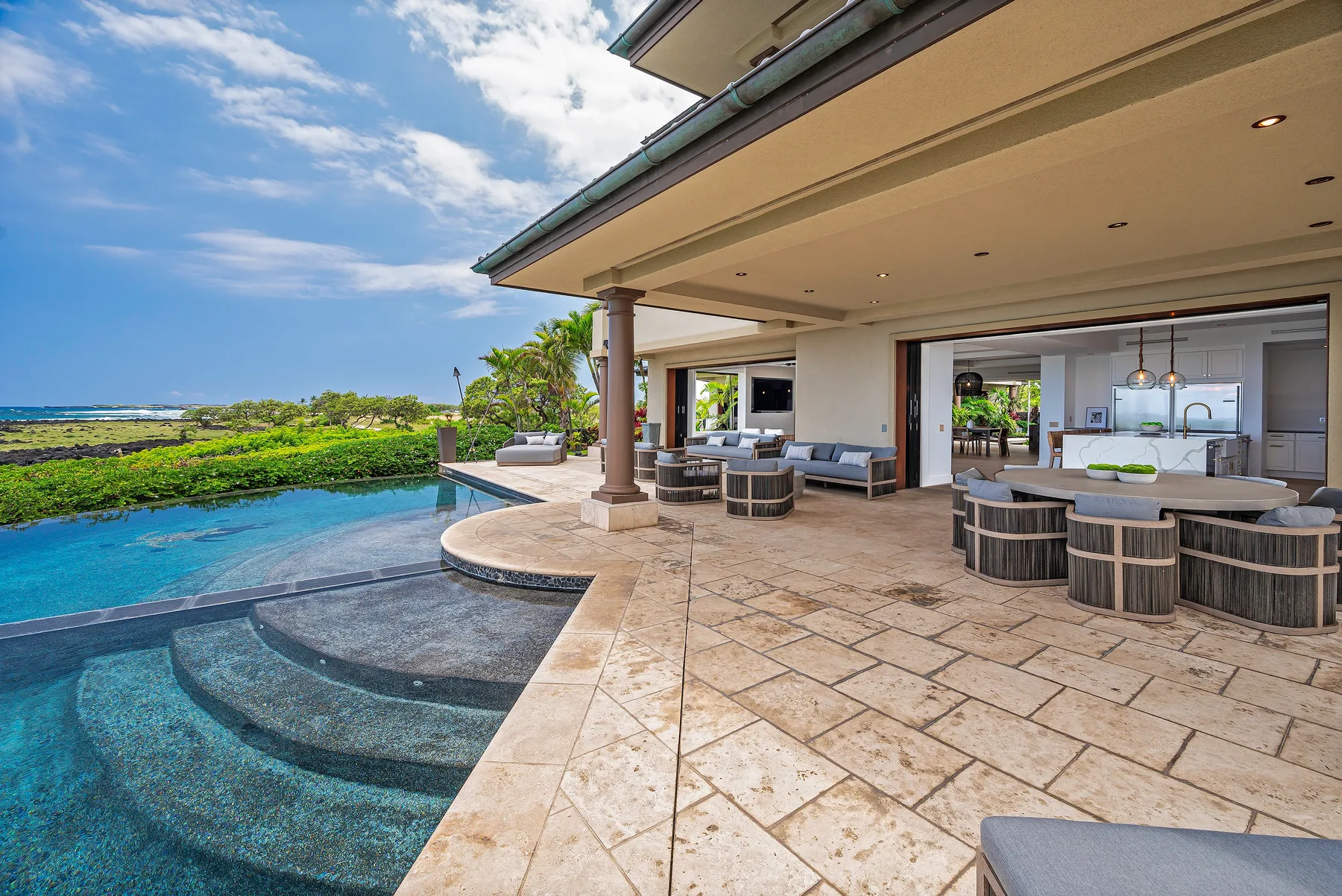 A covered patio overlooks a swimming pool, with outdoor seating and an open living area.