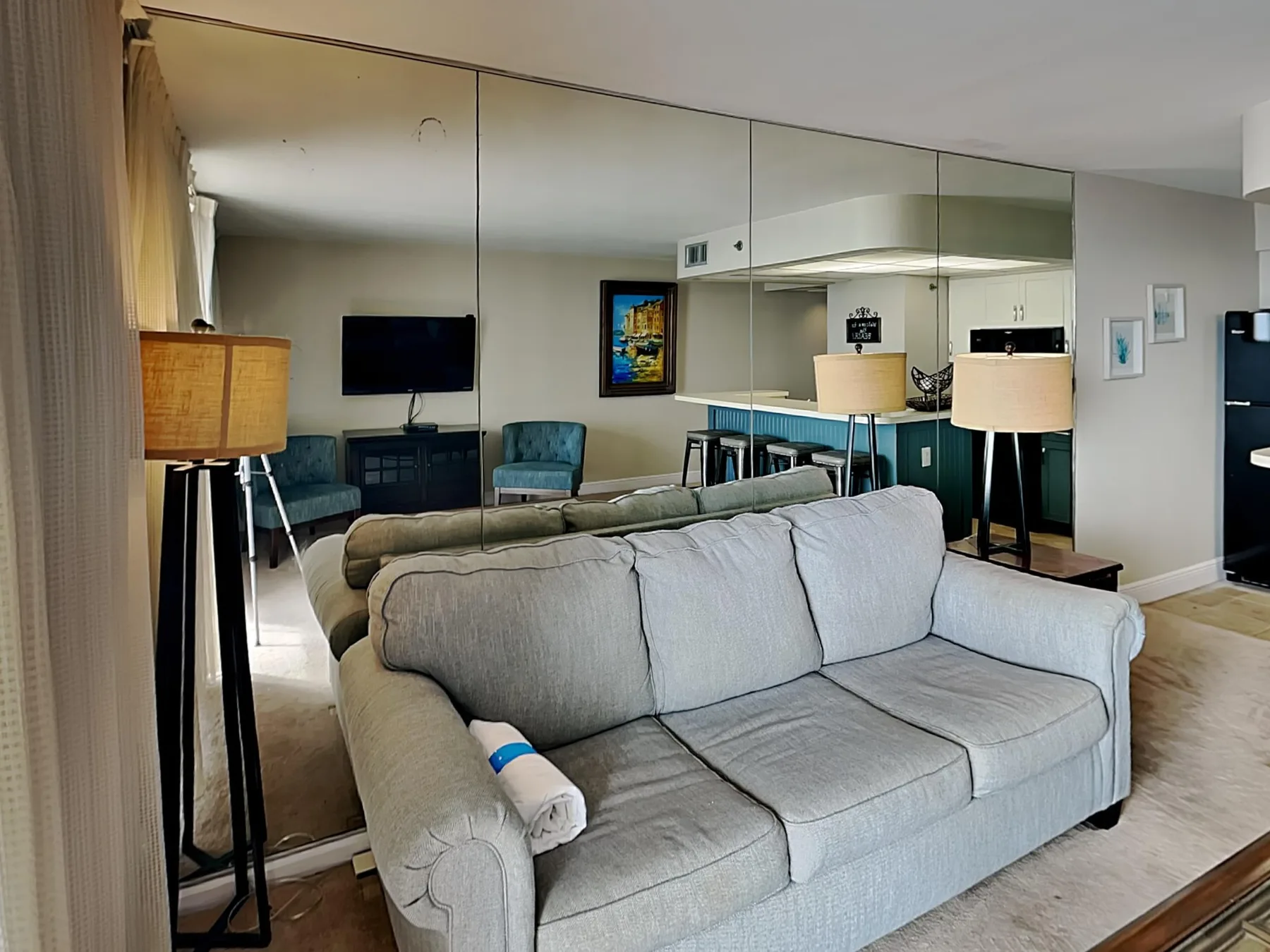 Living room with a light-colored sofa and mirrored wall.