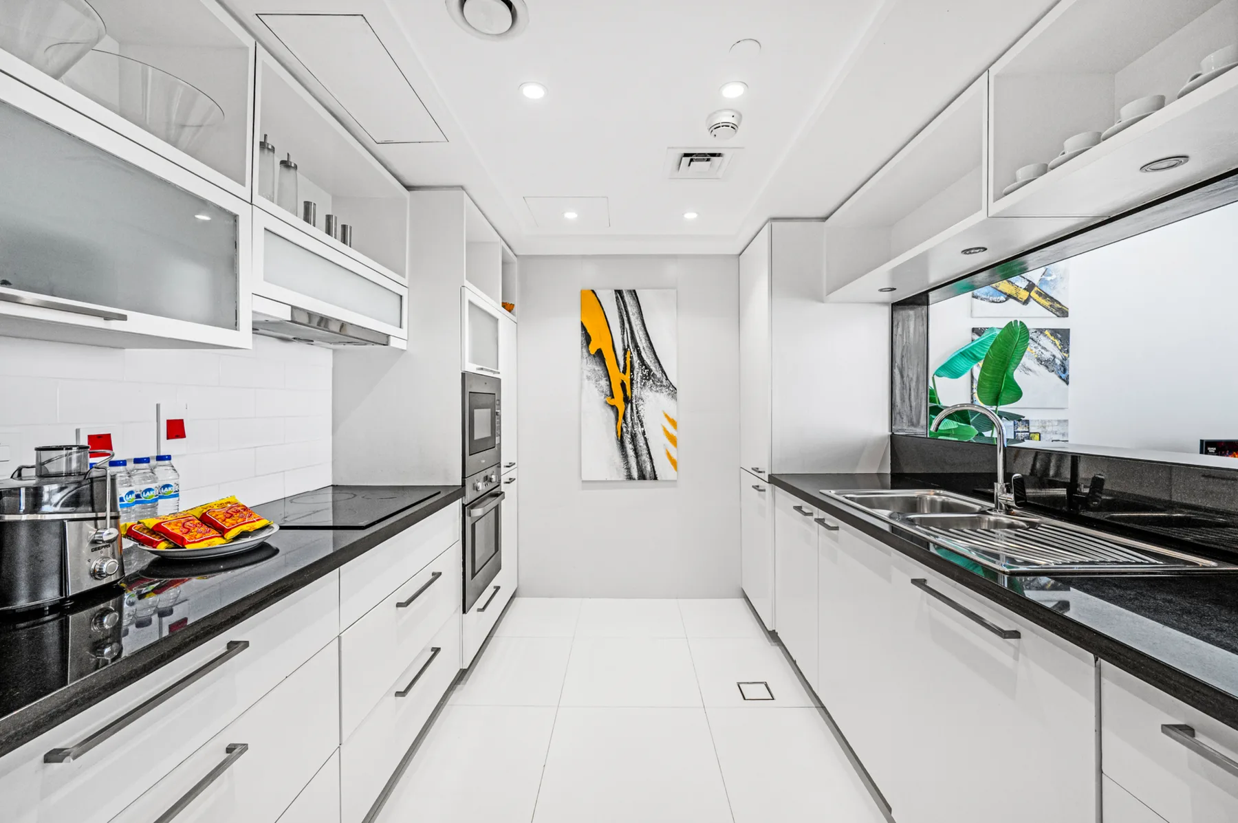 Una cocina moderna con gabinetes blancos y encimeras oscuras.
