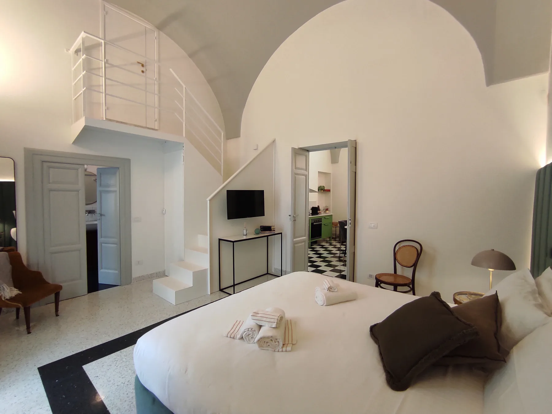 Un dormitorio con una cama grande bajo un techo alto abovedado.