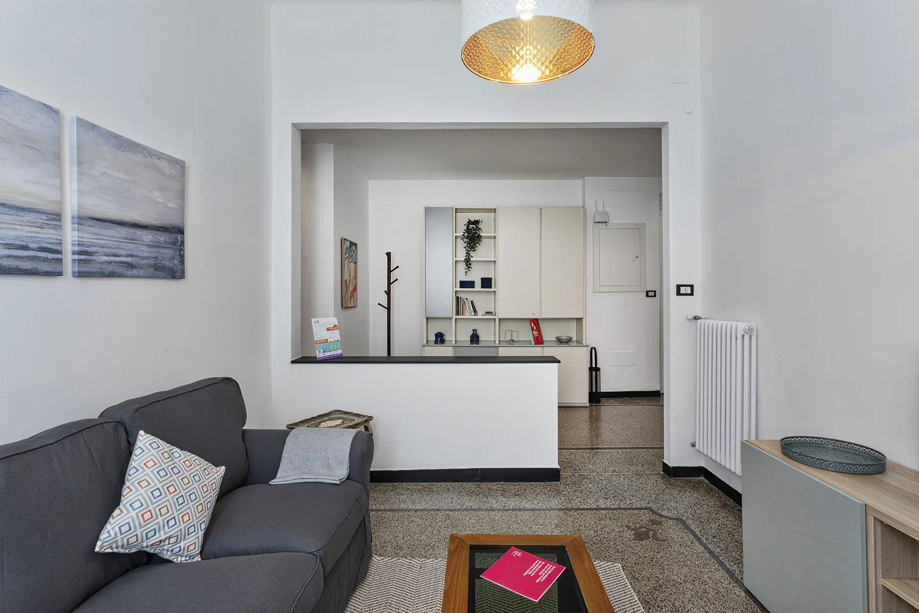 A bright living area with seating and a counter opening onto a small kitchen.