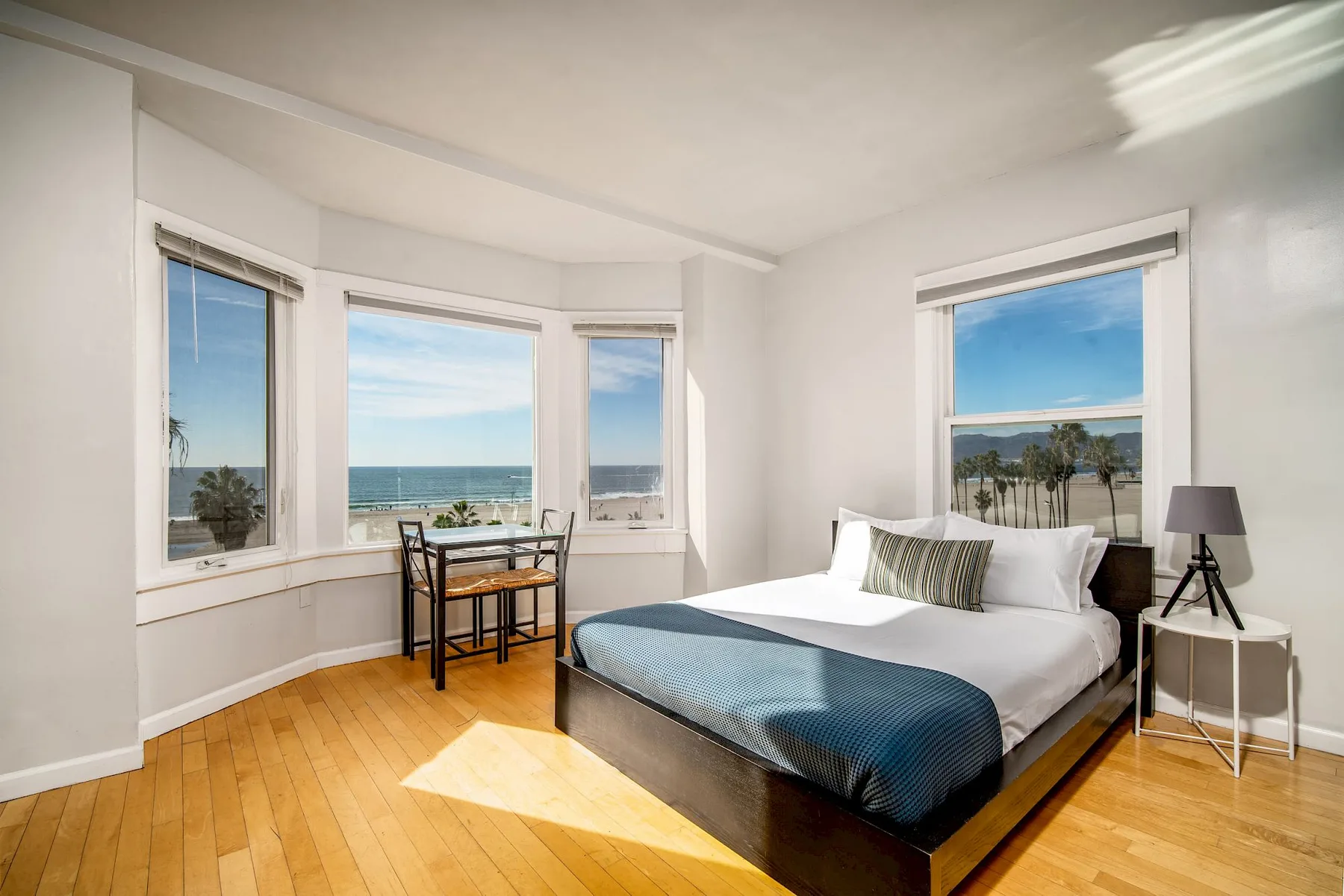 Dormitorio con cama de plataforma y ventanas con vistas al mar.