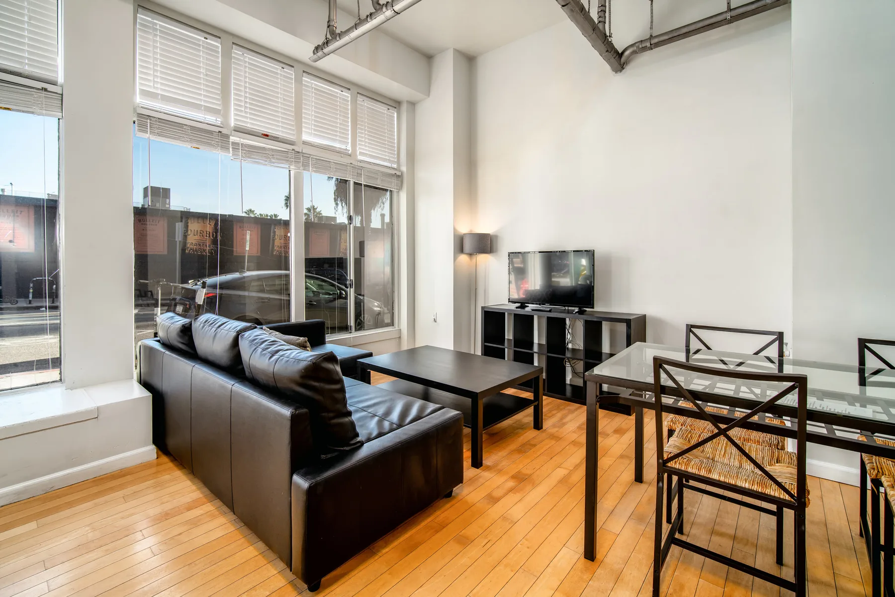 Sala de estar con sofá, mesa de centro, televisor, mesa de comedor y ventanas.