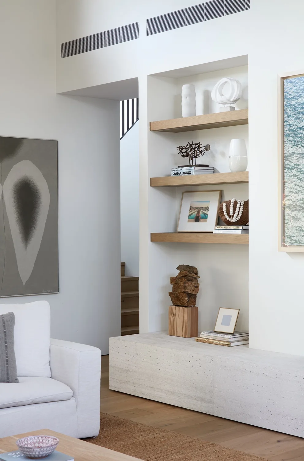 A bright living room with built-in shelves displaying books and decorative objects.