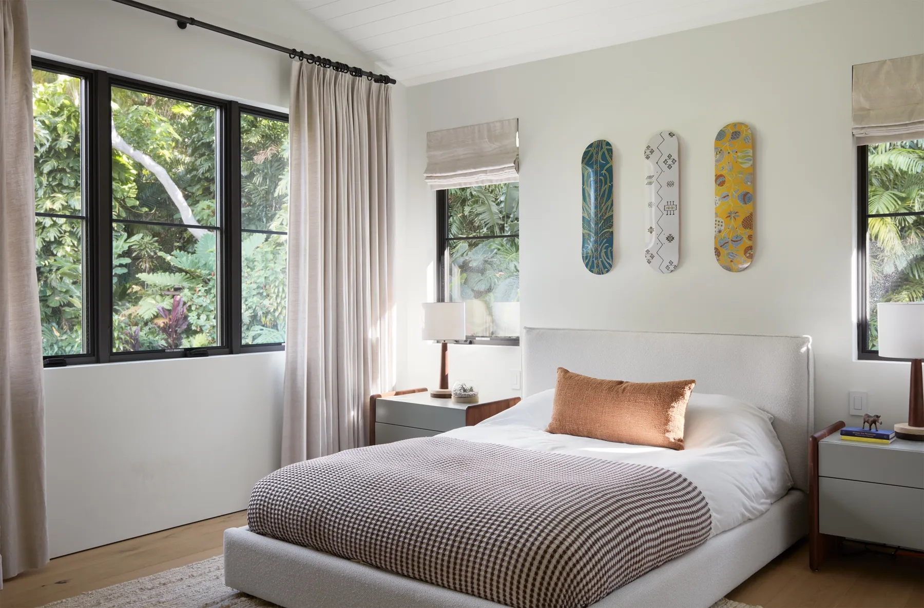 A bedroom with a neatly made bed and three colorful wall decorations.