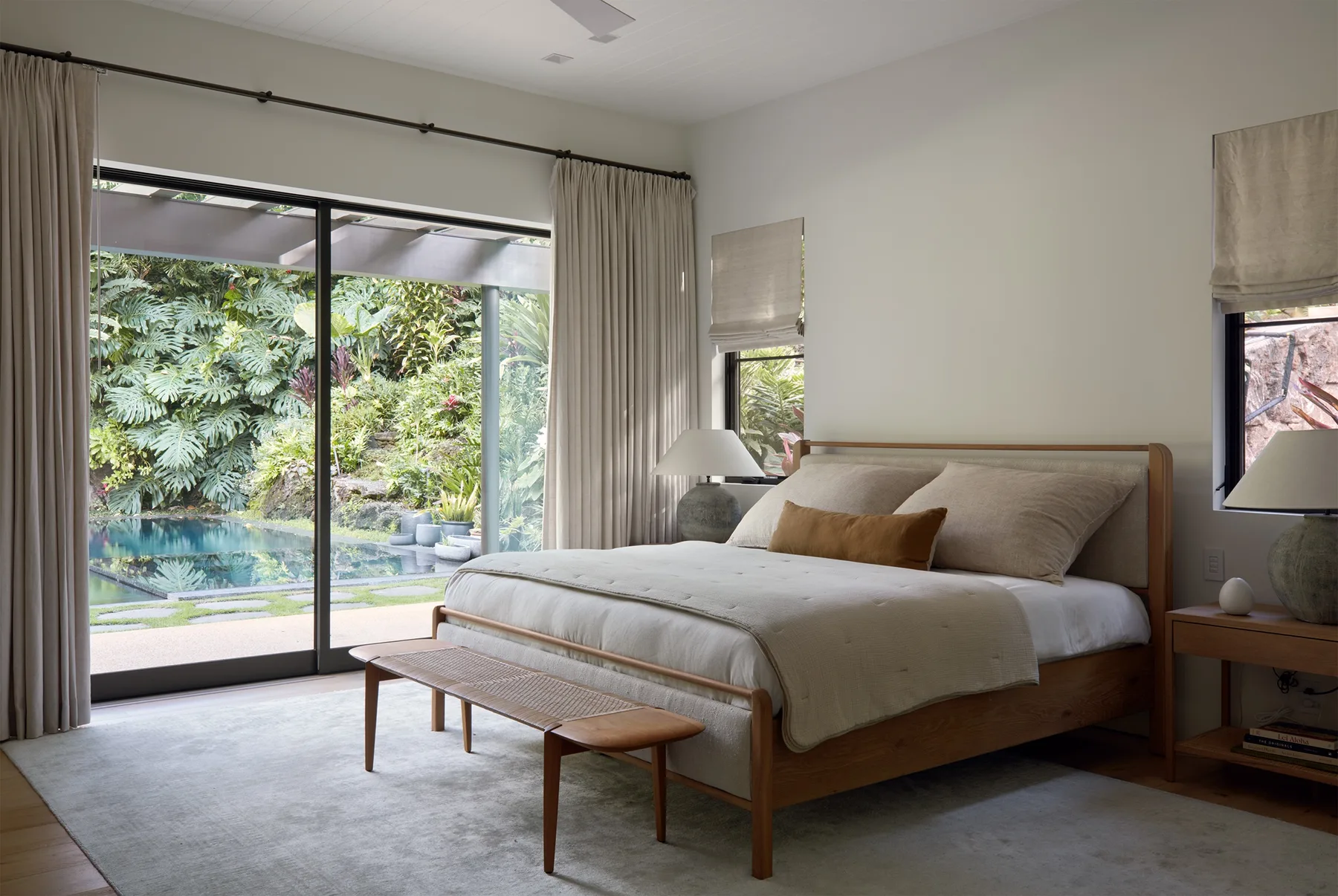 A bedroom with a bed beside large glass doors opening onto a garden.