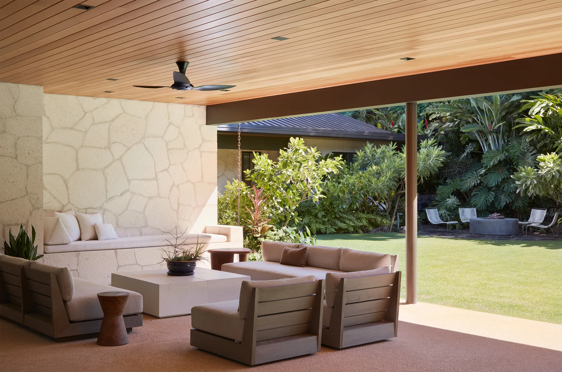 A covered outdoor seating area opens onto a green garden.