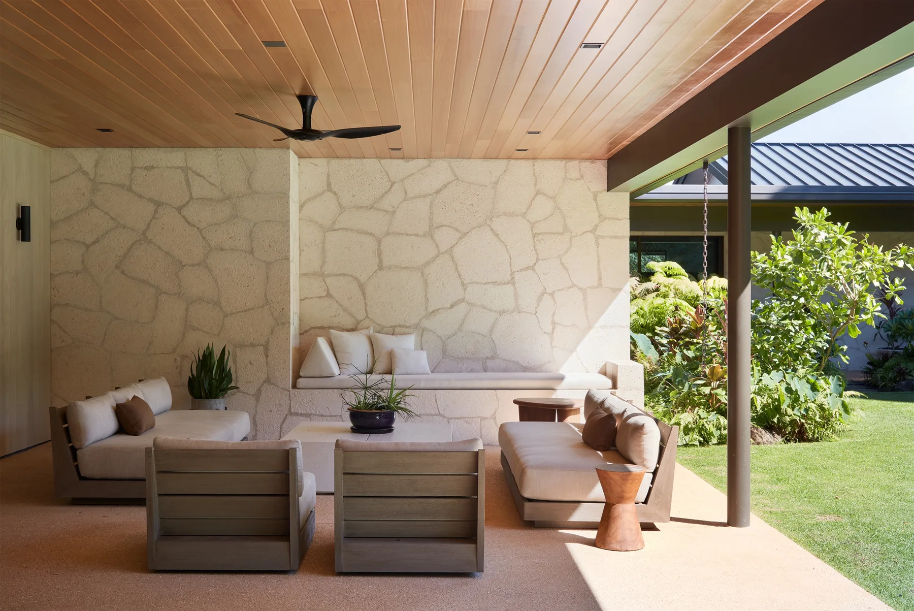 An open-sided lounge with cushioned seating and a garden view.