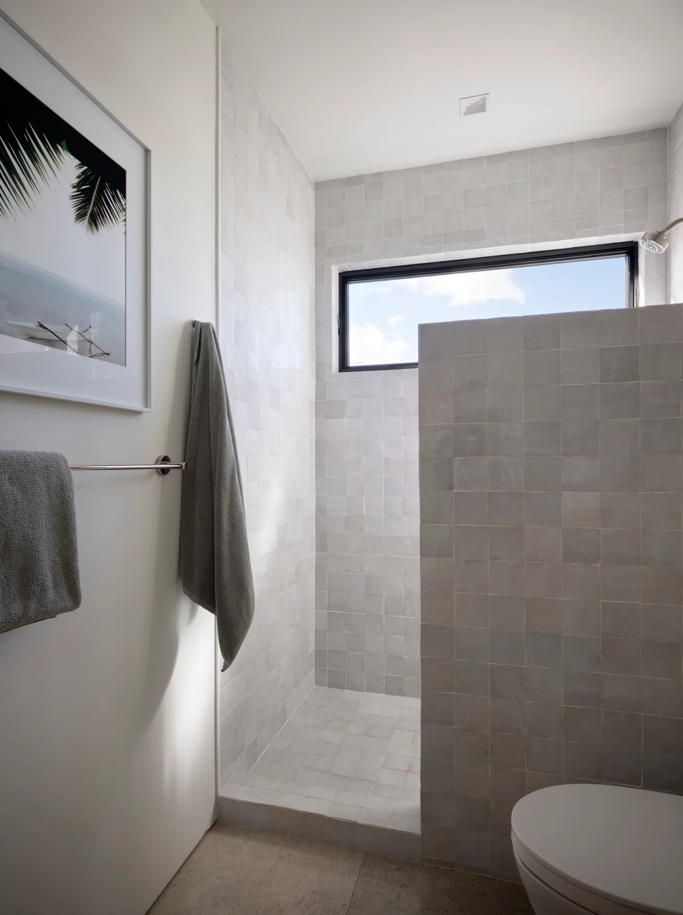 A tiled bathroom with a walk-in shower and a window.