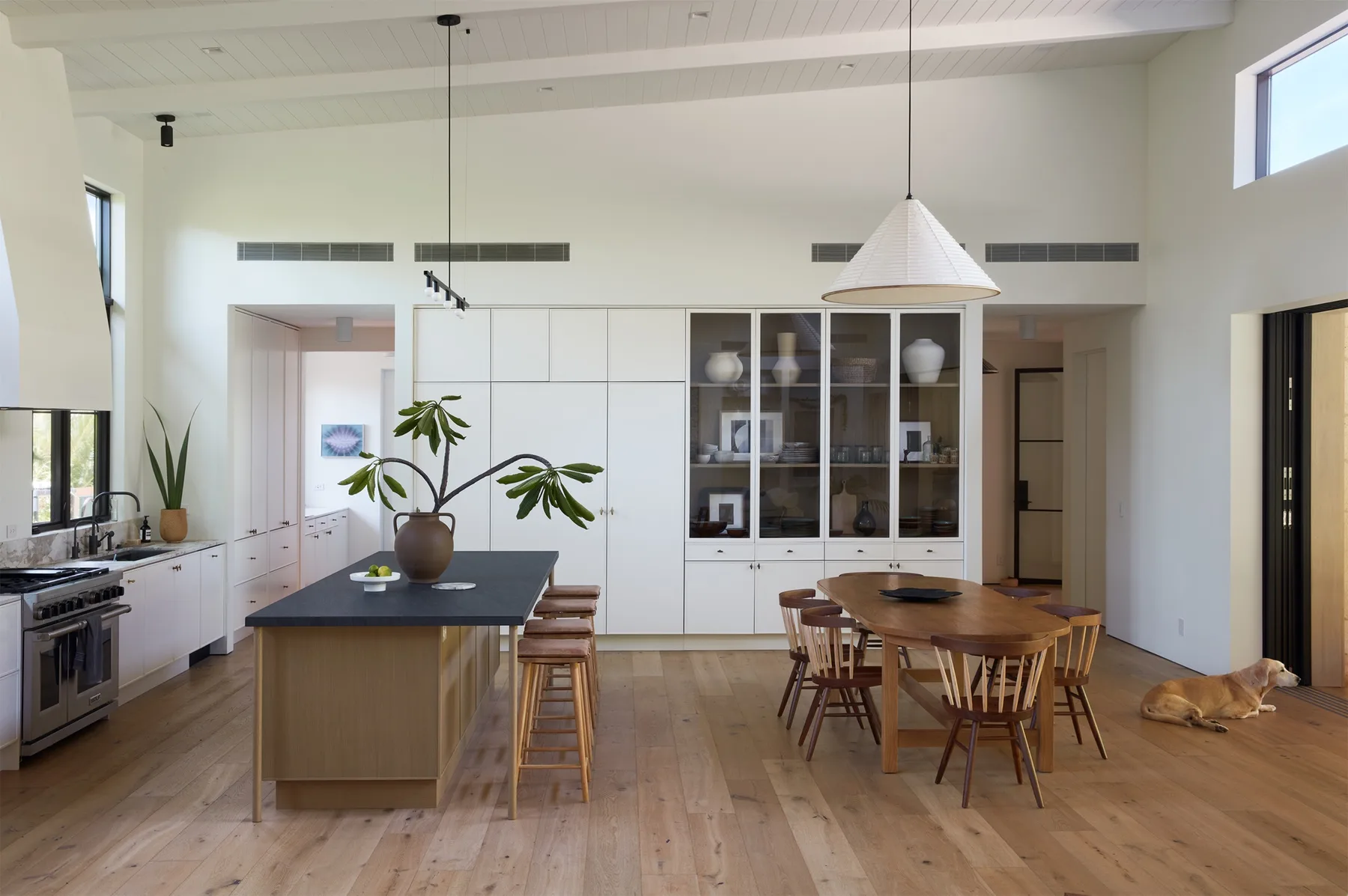 A spacious kitchen and dining area features a central island and a wooden dining table.