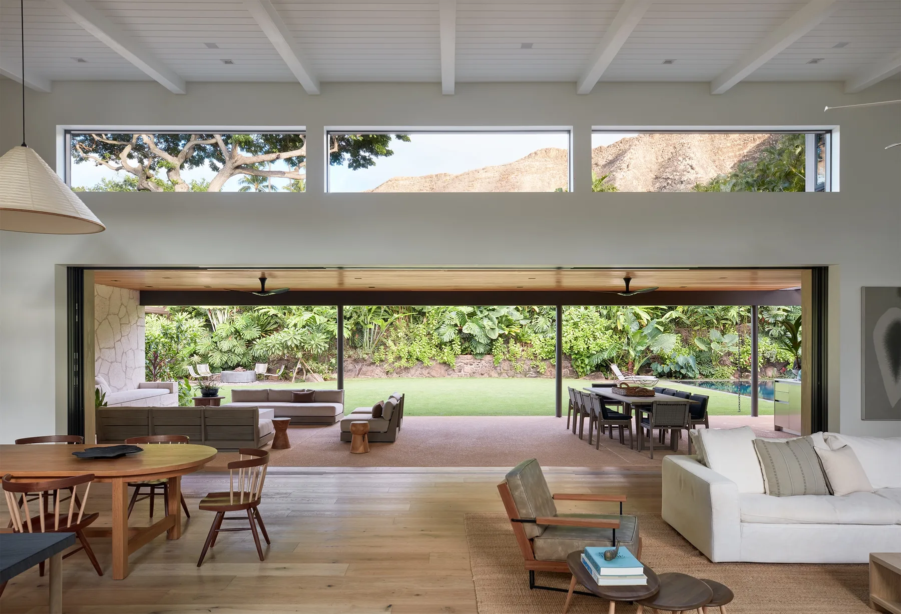 A bright living and dining area opens onto a garden, with broad windows.