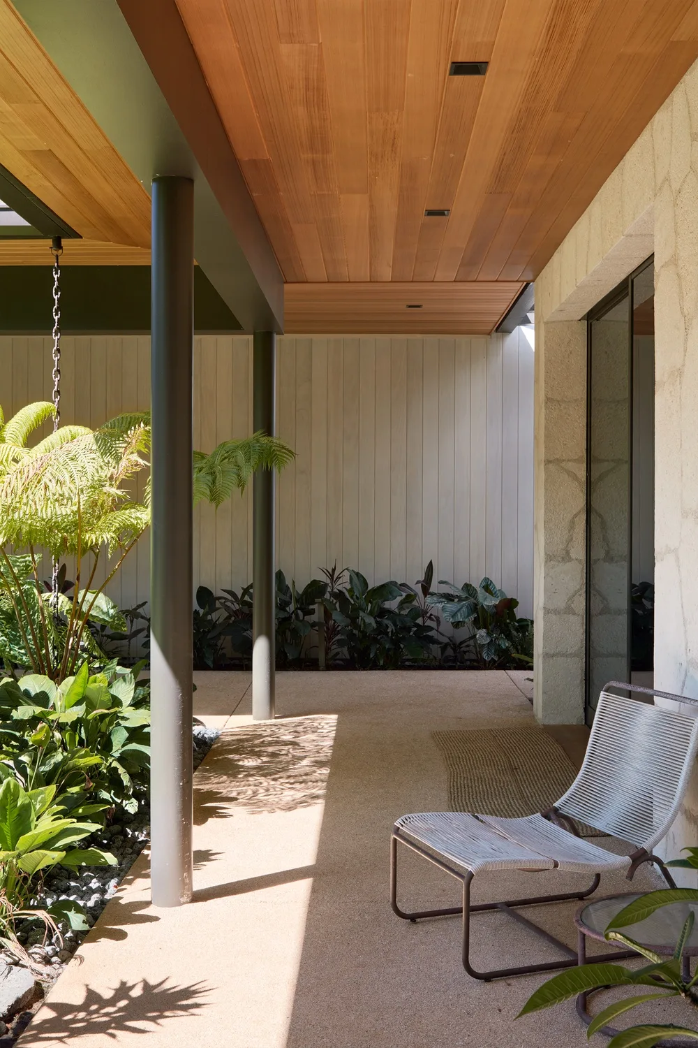 A covered patio with seating, plants, and a wood-paneled ceiling.