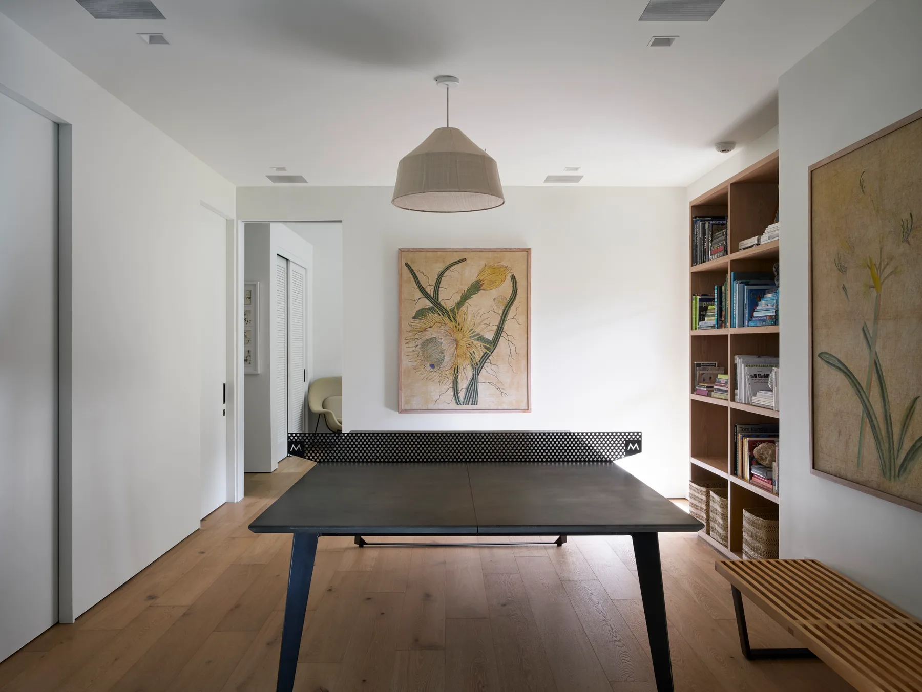 Una habitación luminosa con una mesa grande, estanterías empotradas y cuadros enmarcados.