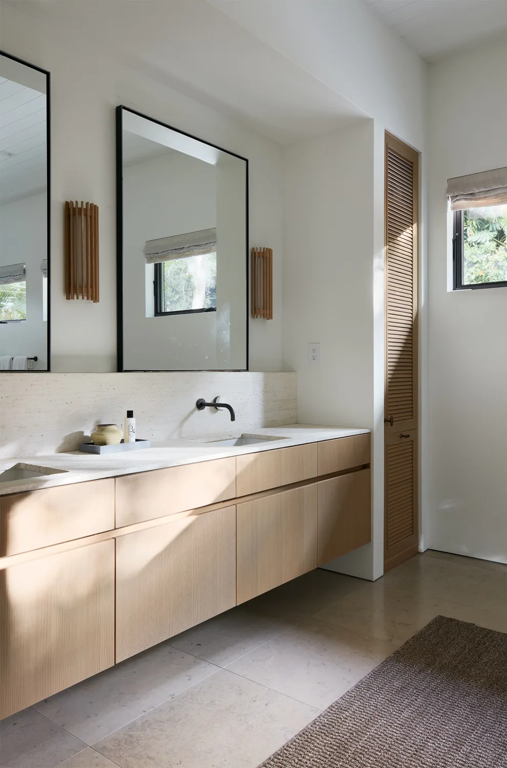 A bright bathroom vanity with a wide mirror and wall-mounted faucet.