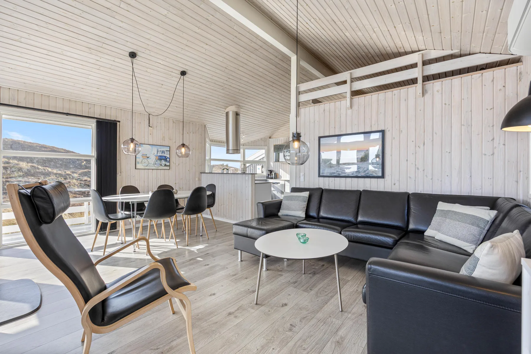 Una sala luminosa con un sofá seccional oscuro y un comedor.