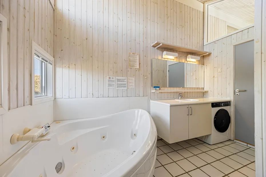 Un baño con una bañera grande y un lavabo junto a una lavadora.