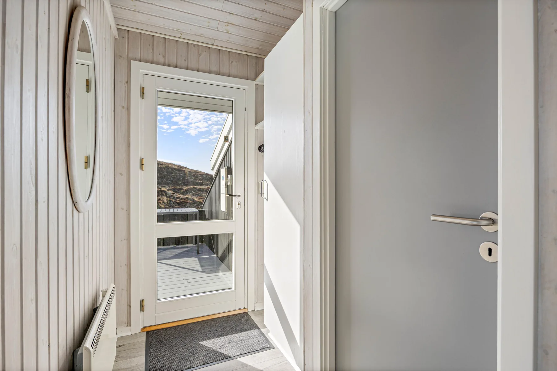 Una entrada luminosa con una puerta de vidrio que da a una terraza exterior.