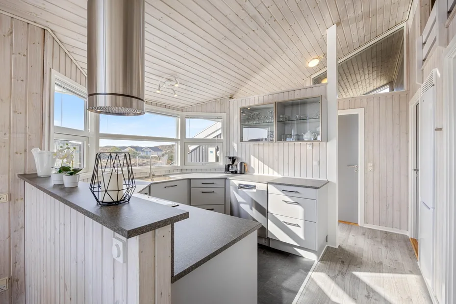Una cocina luminosa con gabinetes claros, ventanas amplias y una isla central.