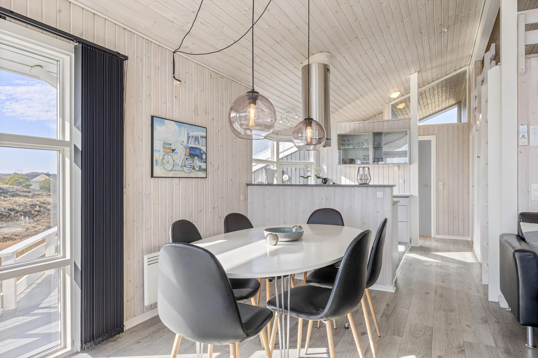 Un comedor luminoso con una mesa y sillas junto a una cocina abierta.