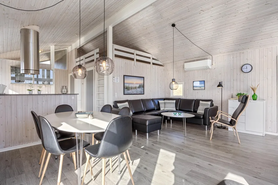Una sala y comedor de planta abierta con un sofá seccional oscuro y una mesa de comedor.